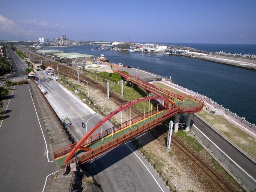 花蓮港景觀橋跨越道路與港區鐵路,旁邊是港灣水域與太平洋